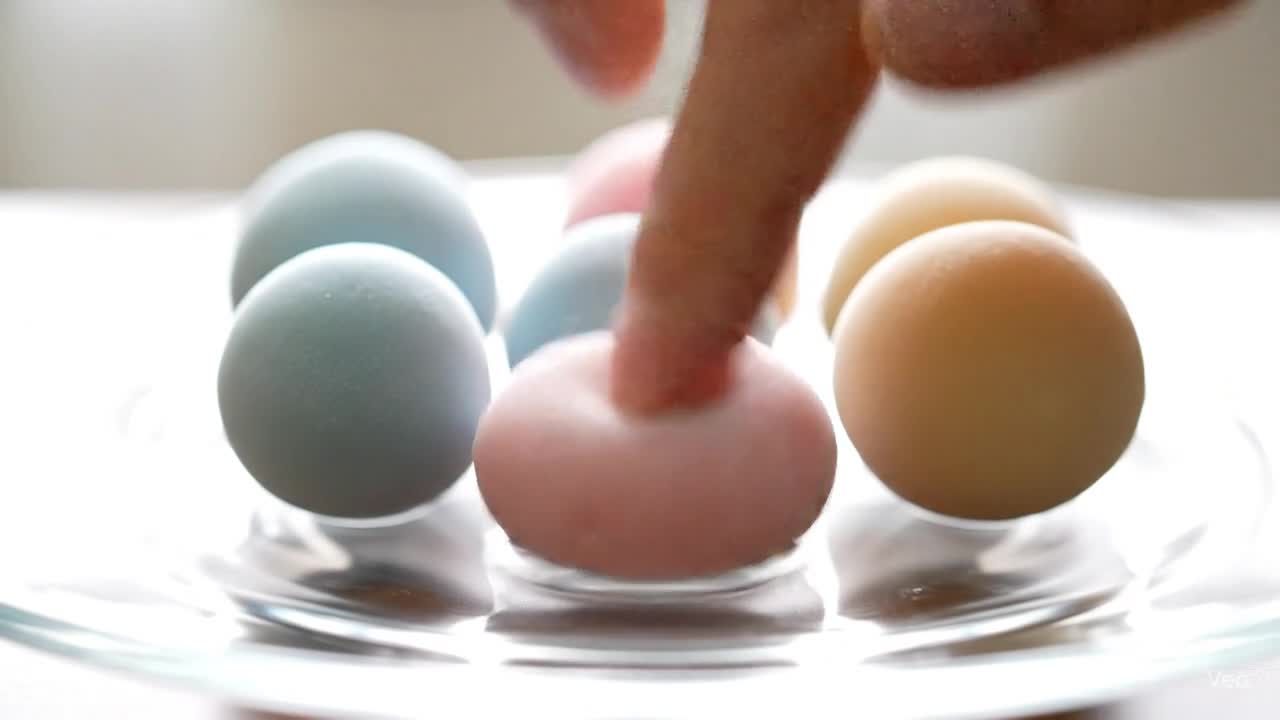 Pastel-colored mochi marbles bouncing and being pressed on a clear glass plate in soft daylight.