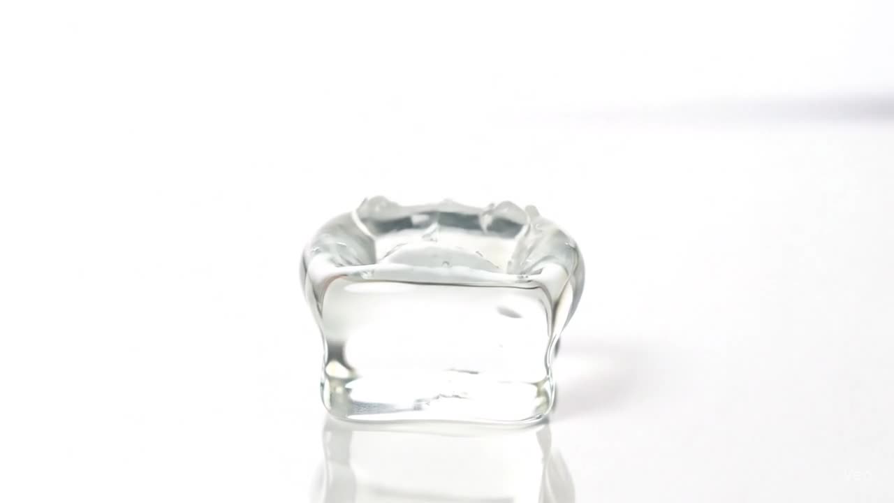 A hand pressing into a large, clear jelly cube, leaving a temporary handprint in a bright, white setting.